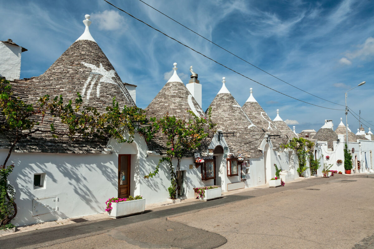Trulli Houses In The Shopping Street In Alberobello Under A Blue Sky Puglia Italy