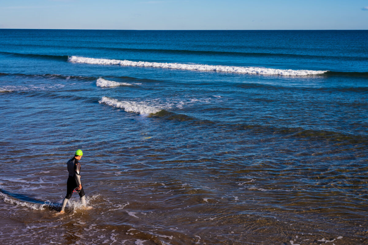Young Athlete Enters The Sea To Swim Wearing A Hat And Wetsuit Joaquincorbalancom